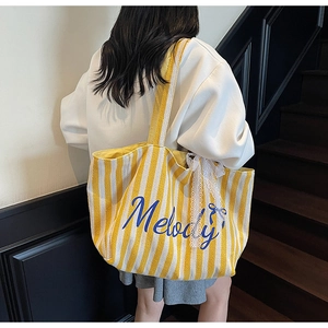 Détail du sac cabas en toile à rayures jaunes et blanches avec imprimé Melody et dentelle