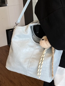 Secchiello azzurro con goffratura a coccodrillo e ciondolo a forma di orso indossato da modella