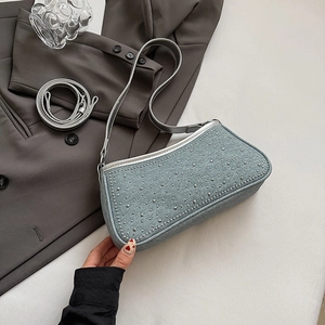 Dettaglio borsa sottobraccio in denim azzurro con borchie argento e finiture in grigio