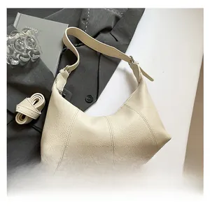 Detailed macro view of the lychee texture leather and strap on the beige hobo bag