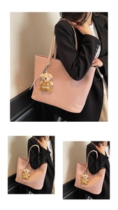 Close-up of pink tote bag showing diagonal textured leather and a cute plush bear charm