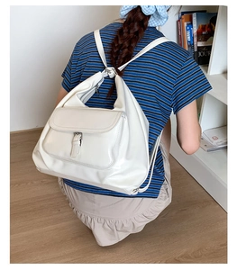 Rear view showing the cream leather convertible backpack styled on a model in a casual setting