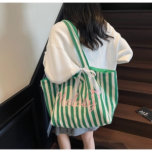 Détail du sac cabas en toile rayé vert et blanc avec écrit Melody rose et nœud en dentelle