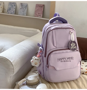 Detail of purple school backpack with plush bear charm and Happy Mind slogan on front