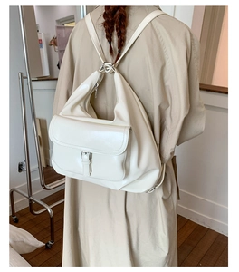 Detail of white glossy leather multi-functional bag showing convertible backpack straps