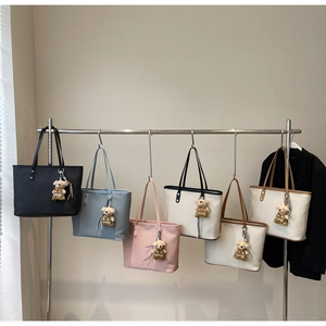 Close-up of minimalist tote bags in various colors featuring cute bear charm accessories