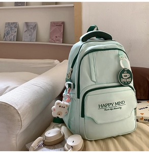 Detail of light green aesthetic backpack showing plush bear charm and side pocket details