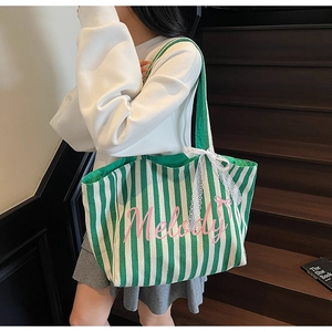 Détail du sac cabas en toile à rayures vertes avec texte Melody et nœud en dentelle