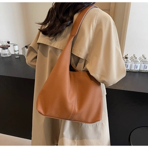 Close-up of brown pebbled leather tote bag worn with a beige trench coat for work