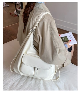 Detail view of large white tote bag with metal buckle and soft glossy leather finish