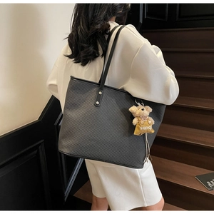 Détail du sac cabas noir avec texture, rivets argentés et charmant pendentif ours