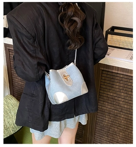Chic blue denim bucket bag with silver leather trim worn over a classic black blazer