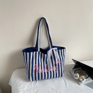Détail du sac cabas en toile rayée bleue avec imprimé Melody rose et ruban dentelle
