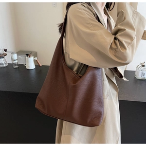 Macro detail of large brown leather tote bag showing rich lychee grain texture and minimalist design