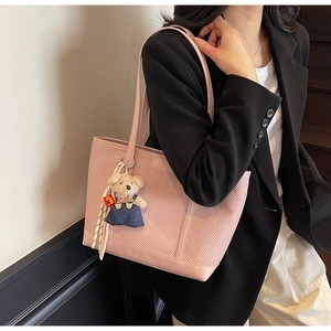 Detail of pink tote bag with herringbone texture and a cute teddy bear charm pendant