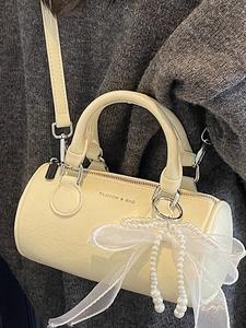 Creamy Boston-style barrel bag with pearl bow charm and detachable shoulder strap