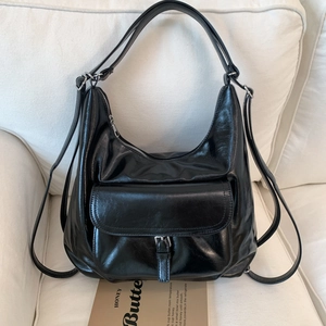 Detail of black glossy faux leather tote showing the texture and metal zipper closure