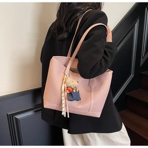 Detail view of pink tote bag with bear charm pendant and tassel on office staircase