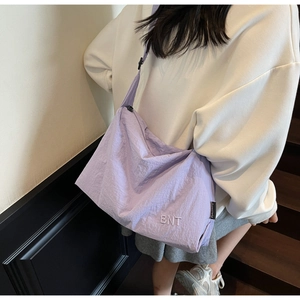 Detail view of large lavender canvas crossbody bag with white BNT embroidery and wide strap