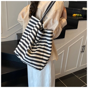 Détail du sac cabas rayé en toile avec boucle en bronze et grande capacité de rangement