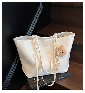 Nahaufnahme der weißen Handtasche in Krokodiloptik mit braunem Teddybär-Anhänger