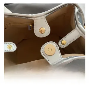 Detail view of silver bucket bag featuring metal magnetic closure and interior zipper pocket