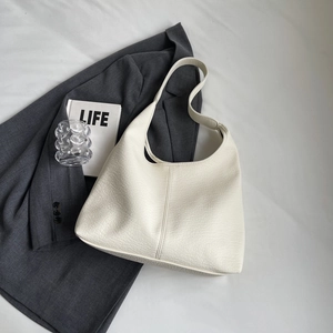 Close-up of cream pebble leather Hobo bag on grey blazer with minimalist prop styling