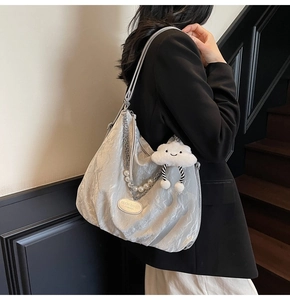 Detail of silver-grey textured shoulder bag with pearl chain and cute cloud pendant