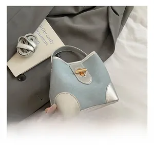 Detail of light blue bucket bag with silver panels and gold twist lock on grey blazer