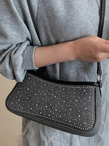 Borsa sottobraccio in denim grigio con borchie argentate e tracolla su una modella