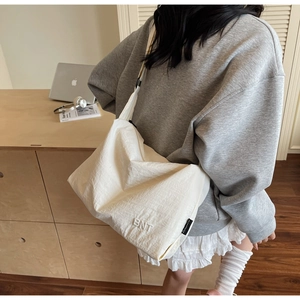 Detailed embroidery of BNT logo on a large ivory canvas crossbody bag for daily use