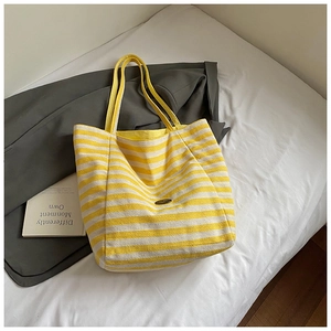 Détail du sac cabas en toile à rayures jaunes avec une plaque métallique ovale