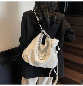 Detail of white pleated shoulder bag with pearl charms, metal chains and a cloud plushie