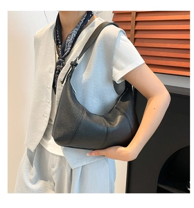 Detail of black pebbled leather texture on crescent hobo bag with silver hardware