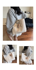 Detail der cremeweißen Totebag mit Krokoprägung und braunem Teddybär-Anhänger als Zubehör