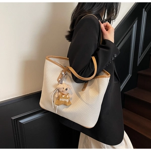 Détail du sac cabas en sergé blanc cassé avec lanières en cuir brun et pendentif ours