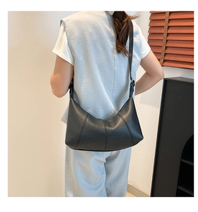 Detail of black crescent hobo bag with pebble leather texture and adjustable strap