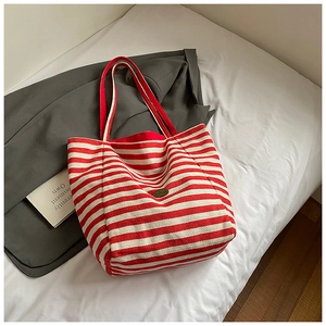 Détail d'un sac cabas en toile rayé rouge et blanc avec une plaque nominative vintage
