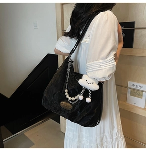 Detail of black pleated tote bag with pearl chain decoration and plush cloud pendant