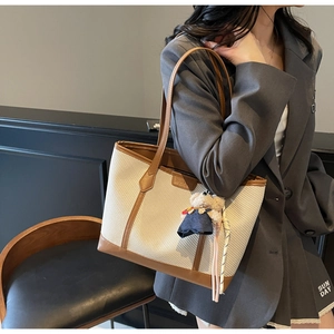 Detail view of woven tote bag with brown leather trim and cute bear charm