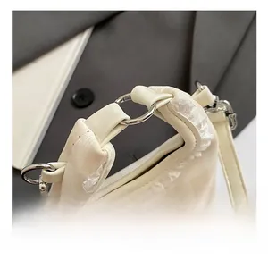 Detail of metal ring handle and cute koala embroidery on white lace bucket bag