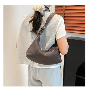 Detailed back view of a dark brown crescent bag showing pebbled leather and wide strap