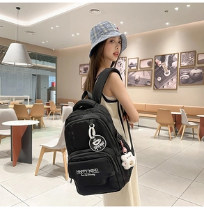 Detail of black nylon backpack with HAPPY MIND text and cute bear charms in cafe setting