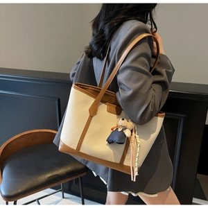 Detail shot of large cream canvas tote with brown leather trim and cute bear charm