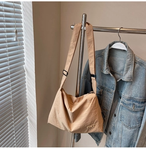 Detail view of beige canvas crossbody bag with BNT embroidery and adjustable strap