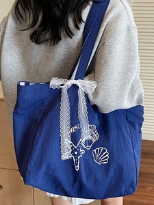 Sac cabas en toile rayée bleu marine avec un nœud en dentelle blanche et motifs marins