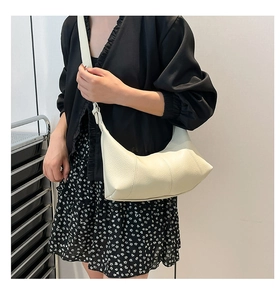 Detailed side view of cream pebbled leather baguette bag with vertical stitching