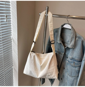 Detailed close-up of large canvas travel bag with BNT embroidery on beige textured fabric