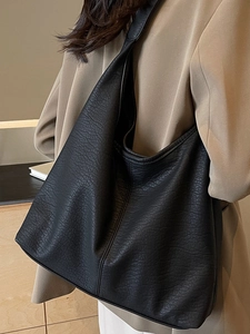 Minimalist black lychee texture leather tote bag worn by model in business casual suit