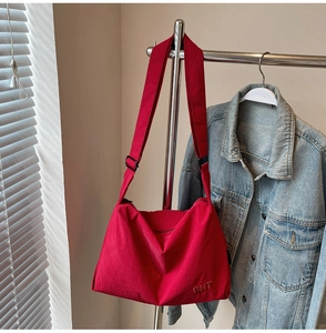 Detail view of red canvas crossbody bag with BNT embroidery and adjustable shoulder strap